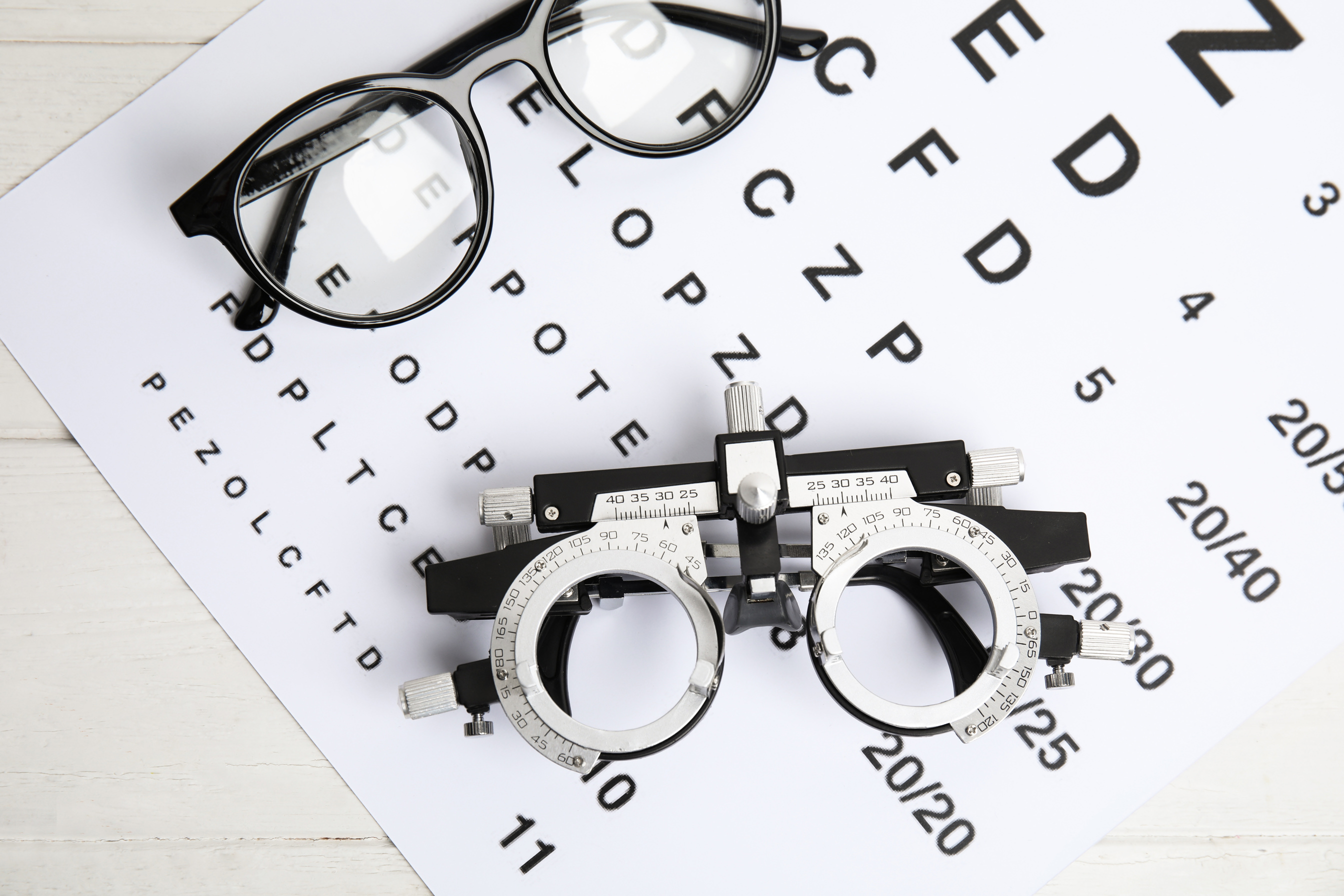 Trial Frame, Eye Chart Test and Glasses on White Wooden Table, T